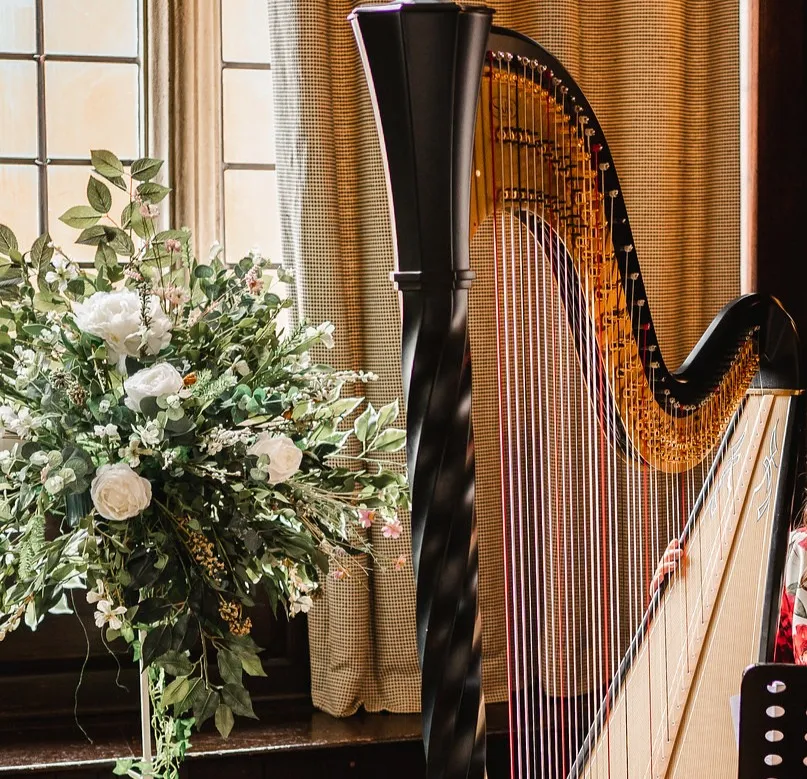 Angharad and her harp next to a lovely bouquet of flowers.